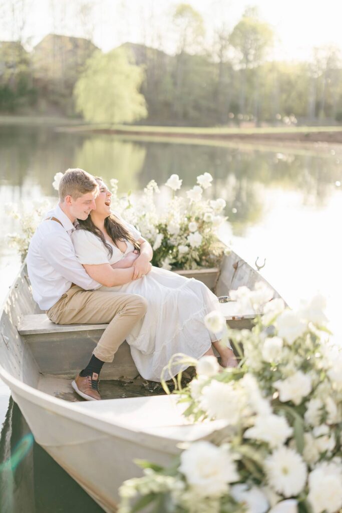 NC Engagement Photos in a canoe with white florals on lake