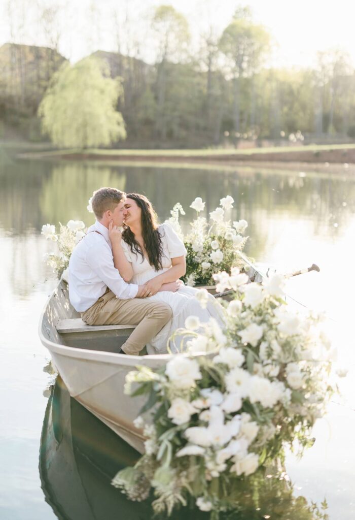 NC Engagement Photos in a canoe with white florals on lake