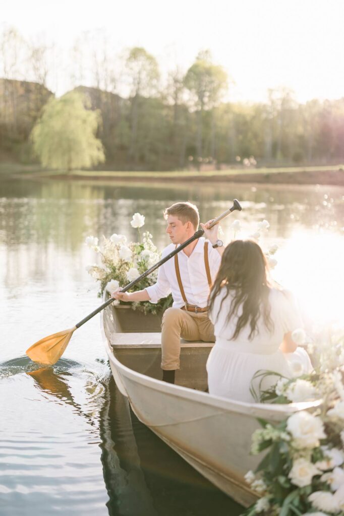 NC Engagement Photos in a canoe with white florals on lake