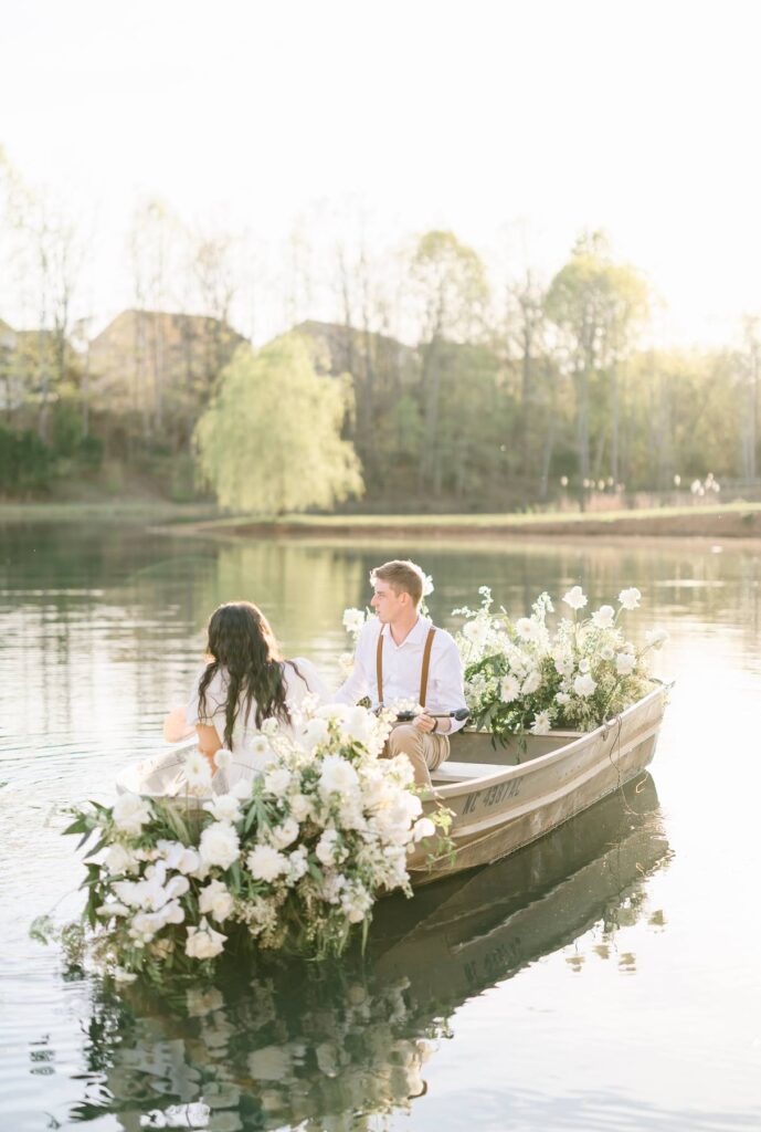 NC Engagement Photos in a canoe with white florals on lake