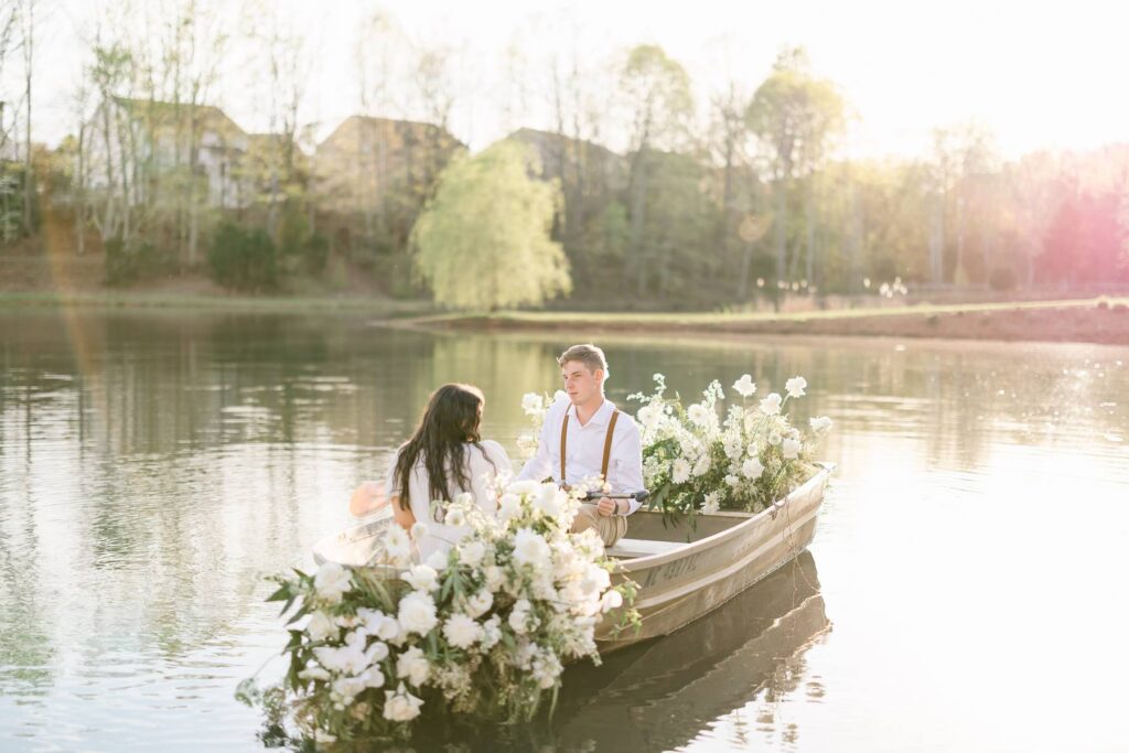 NC Engagement Photos in a canoe with white florals on lake